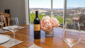 A dining table with wine glasses, a bottle of wine, and a vase of flowers.