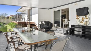An outdoor patio with a glass-top table and wicker chairs, a barbecue grill, and a fireplace. - Guest House on Guy (Forster)