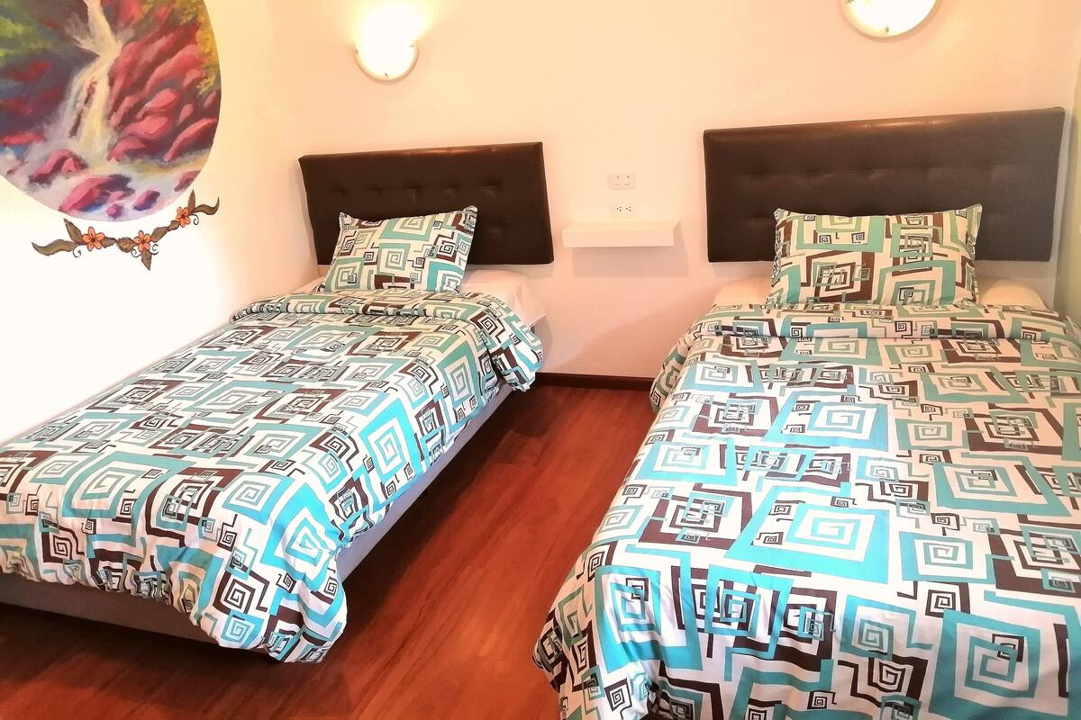 A double room with two beds, each with patterned bedding and headboards.