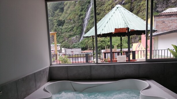 A hot tub with a view of a waterfall and a gazebo.