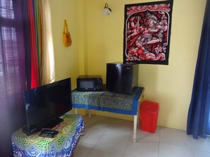 Un petit salon équipé d’un téléviseur, d’un four à micro-ondes et d’une table recouverte d’une nappe à motifs.