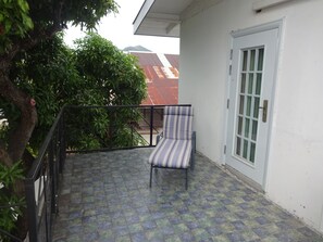 A balcony with a chair, a door, and a tree. - Secret Haven TnT (Port of Spain)