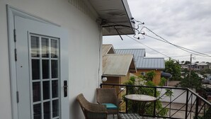 A balcony with wicker furniture, a small table, and a door with a glass panel. - Secret Haven TnT (Port of Spain)