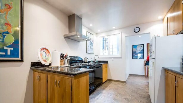 A kitchen with wooden cabinets, a stove, and a refrigerator.