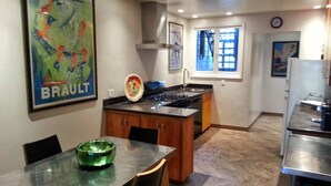 A compact kitchen with a dining area, featuring a stove, sink, and a refrigerator.