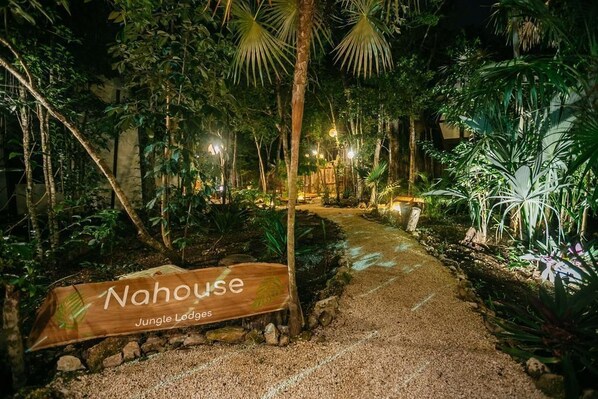 Ein Pfad führt zu einem Holzschild mit der Aufschrift 'Nahouse Jungle Lodges'.