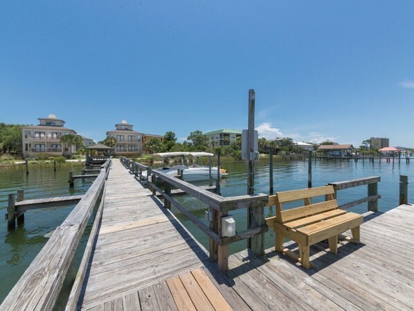 A wooden pier extending into calm water, with a wooden bench at the end.