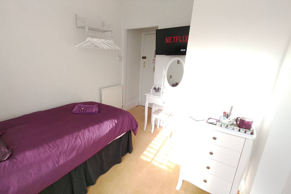 A bedroom with a bed, a dresser, a mirror, and a door with a Netflix sign.