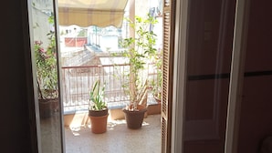 An open sliding door to a balcony with potted plants and a metal railing. - Cosy Penthouse (up to 6 guests) in the City Centre! (Thessaloniki)
