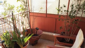 A sunlit outdoor seating area with wooden chairs and potted plants. - Cosy Penthouse (up to 6 guests) in the City Centre! (Thessaloniki)