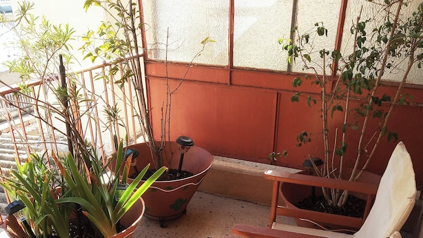 A sunlit outdoor seating area with wooden chairs and potted plants. - Cosy Penthouse (up to 6 guests) in the City Centre! (Thessaloniki)