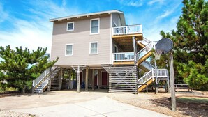A two-story building with a covered patio area, wooden stairs, and a basketball hoop. - Oceanside, Pool, Close to Beach, Sun Decks, OS1E, Seas The Day (Corolla)