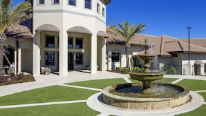 A building with a fountain in the courtyard, surrounded by well-maintained grass and palm trees. - Rolling Skies by VillaDirect (Davenport)