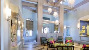 A spacious lobby with high ceilings, wooden beams, and a modern chandelier. There are several seating areas with colorful chairs and a reception desk. - Rolling Skies by VillaDirect (Davenport)