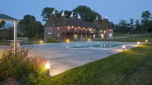Ein großes Haus mit Schwimmbad, umgeben von einem gepflegten Rasen und Garten.