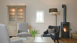 Ein Wohnzimmer mit Kamin, einer Vitrine und einem Fenster, sowie einer Lampe.