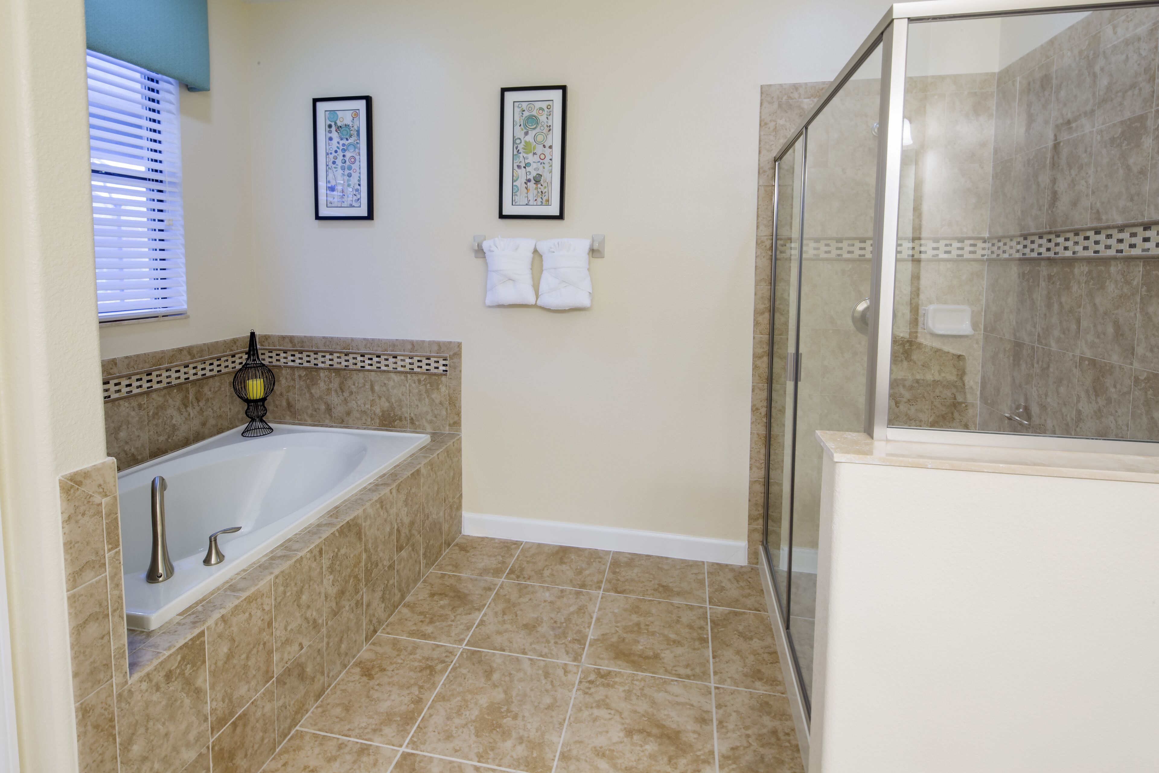 A bathroom with a bathtub, a shower, and two framed pictures on the wall.