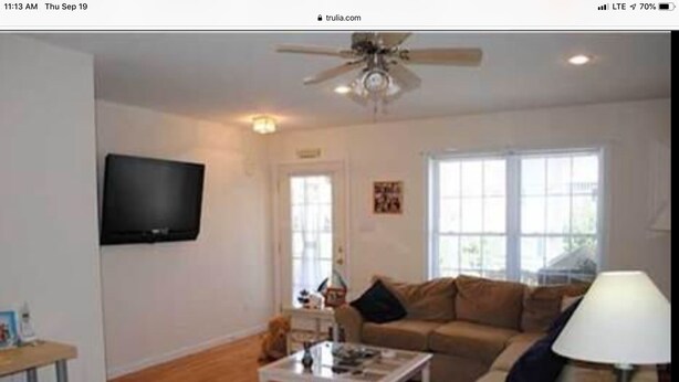 A living room with a sofa, coffee table, TV, and a ceiling fan. - Walk to the ocean and Boardwalk (Seaside Park)