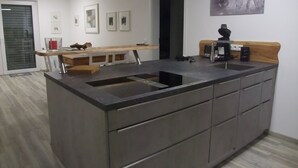 A modern kitchen with a central island, built-in cabinets, and a sink. - Apartment Schönblick (Pfronten-Halden)