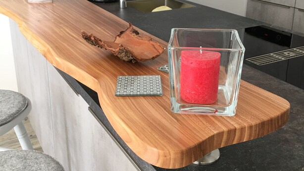 A kitchen counter with a wooden cutting board, a red candle, and a coffee maker. - Apartment Schönblick (Pfronten-Halden)