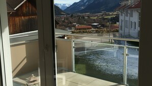 A balcony with a view of mountains, a river, and a town. - Apartment Schönblick (Pfronten-Halden)
