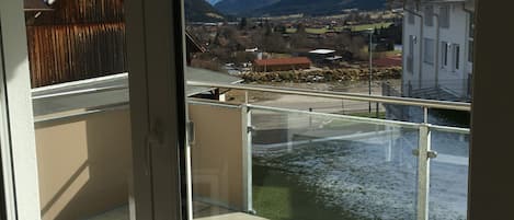 En balkon med udsigt til bjerge, en flod og en by.