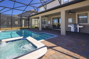 Un espace piscine doté d’un jacuzzi, de mobilier de patio et d’un barbecue.