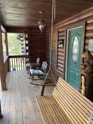 Step into this cozy cabin, featuring a porch with a swing chair and bench, perfect for relaxing.