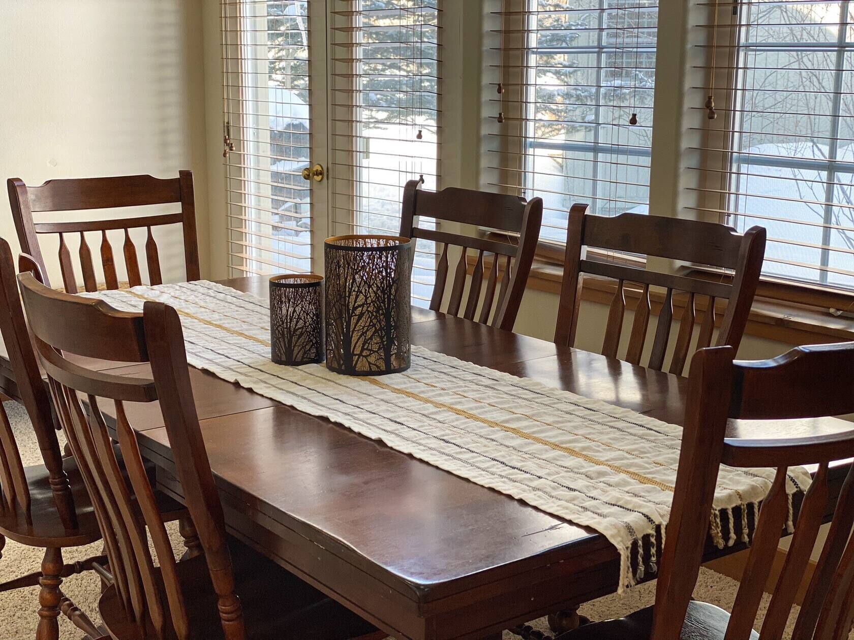 A dining table with a woven placemat, surrounded by wooden chairs.