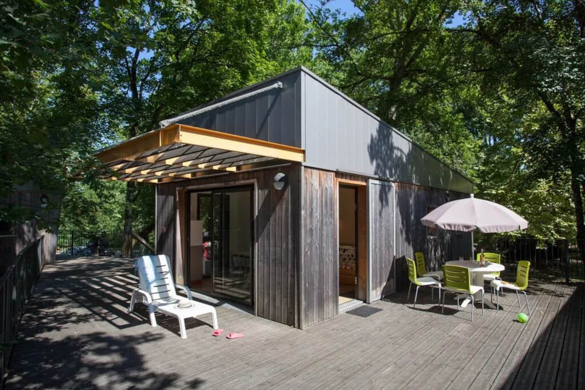 A modern outdoor patio with a pergola, a dining table with chairs, and a small seating area with a chair and a table.