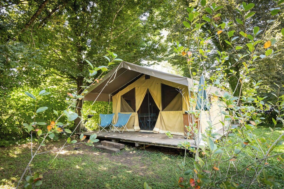 A tented accommodation with a platform and two chairs.