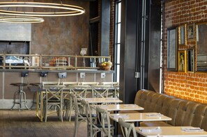 A restaurant interior with brick walls, wooden tables, and a bar area. - HOTEL CERRO, Autograph Collection (San Luis Obispo)