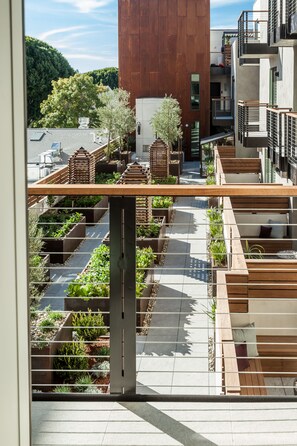 A rooftop garden with wooden planters and seating areas, surrounded by modern buildings.