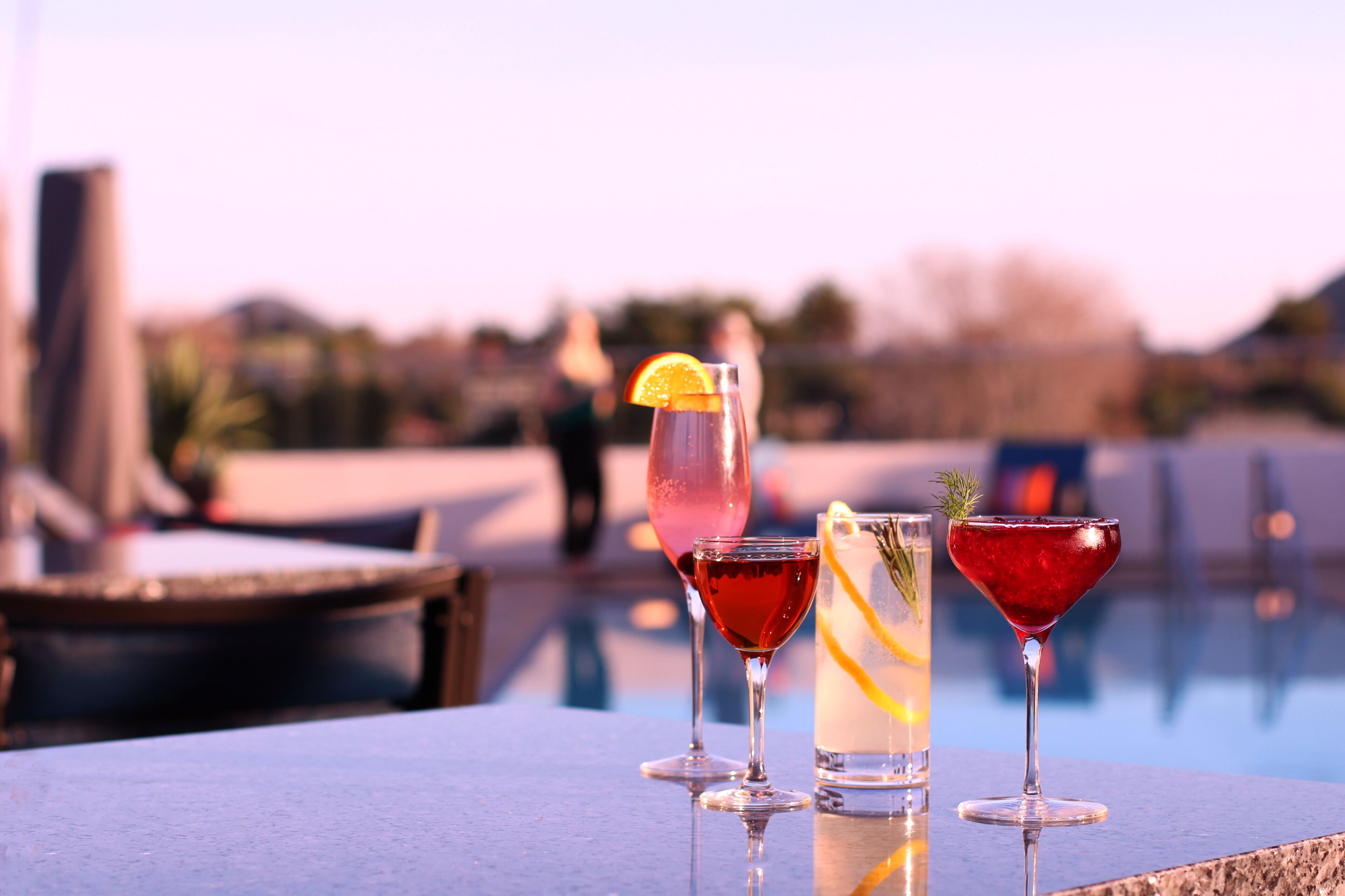 Tres bebidas sobre una mesa junto a una piscina.