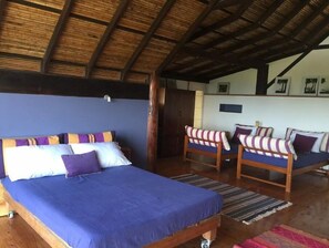 A room with a bed, two sofas, and a wooden ceiling.