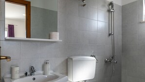 Kylpyhuone, jossa on valkoinen pesuallas, wc ja suihku.