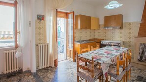 A compact kitchen with wooden cabinets, a gas stove, and a dining table with chairs.