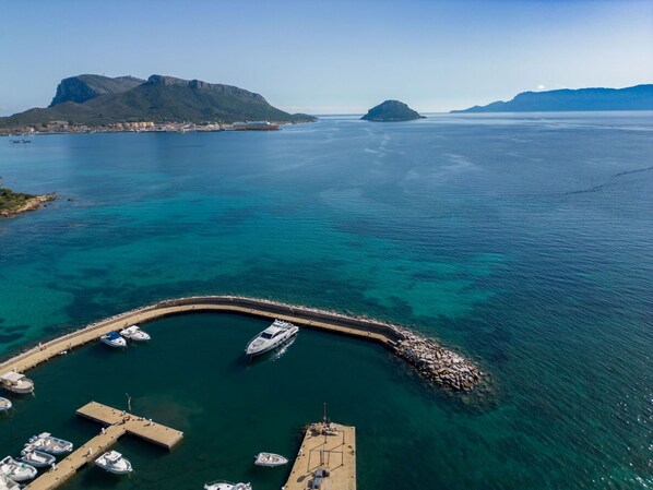 Enjoy serene waterfront views from this tranquil marina, surrounded by boats and a picturesque rocky breakwater.