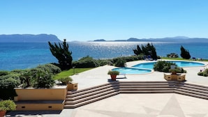 A pool area with steps leading to a pool, surrounded by potted plants and a view of the sea. - Nice apartment for 4 guests with WIFI, pool, TV, terrace and pets allowed (Regia Dogana)