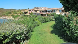 A coastal property with multiple buildings, a grassy pathway, and a view of the sea. - Nice apartment for 4 guests with WIFI, pool, TV, terrace and pets allowed (Regia Dogana)