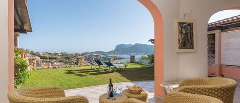 Una terraza con muebles de mimbre, vista al mar y un cuadro en la pared.