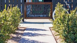 A pathway leading to a building with a wooden fence and a green door. - Kauai-Inspired California Beach Retreat, Unit 1 (Oceanside)
