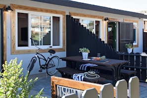 A patio area with a wooden table, benches, and a bicycle. - Kauai-Inspired California Beach Retreat, Unit 2 (Oceanside)