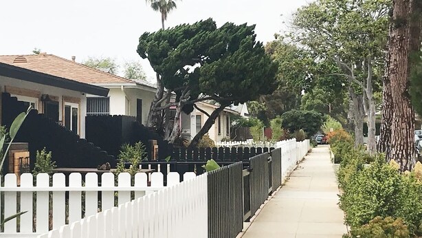 A residential street with houses, a white picket fence, and a sidewalk. - Kauai-Inspired California Beach Retreat, Unit 2 (Oceanside)