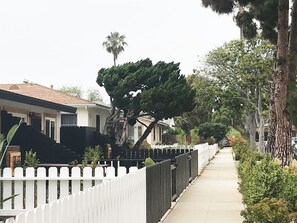 A residential street with houses, a white picket fence, and a sidewalk. - Kauai-Inspired California Beach Retreat, Unit 2 (Oceanside)