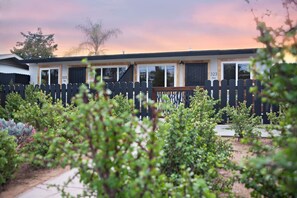 Une rangée de maisons mobiles, avec une clôture en piquets noirs au premier plan.