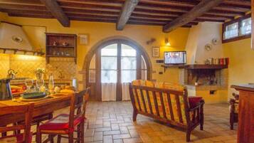 Una cucina rustica con un tavolo di legno, sedie e un televisore.