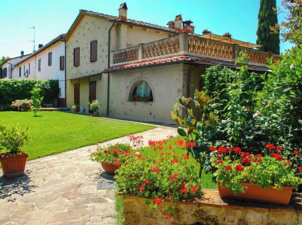 A traditional building with a stone pathway leading to a well-maintained lawn and flower beds.