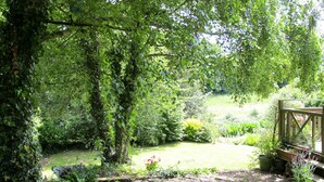 Un jardin luxuriant avec un sentier de pierres menant à une terrasse en bois.