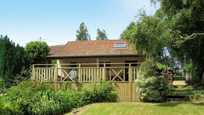 Une maison avec un toit en tuiles, une terrasse en bois et un mur en pierre.